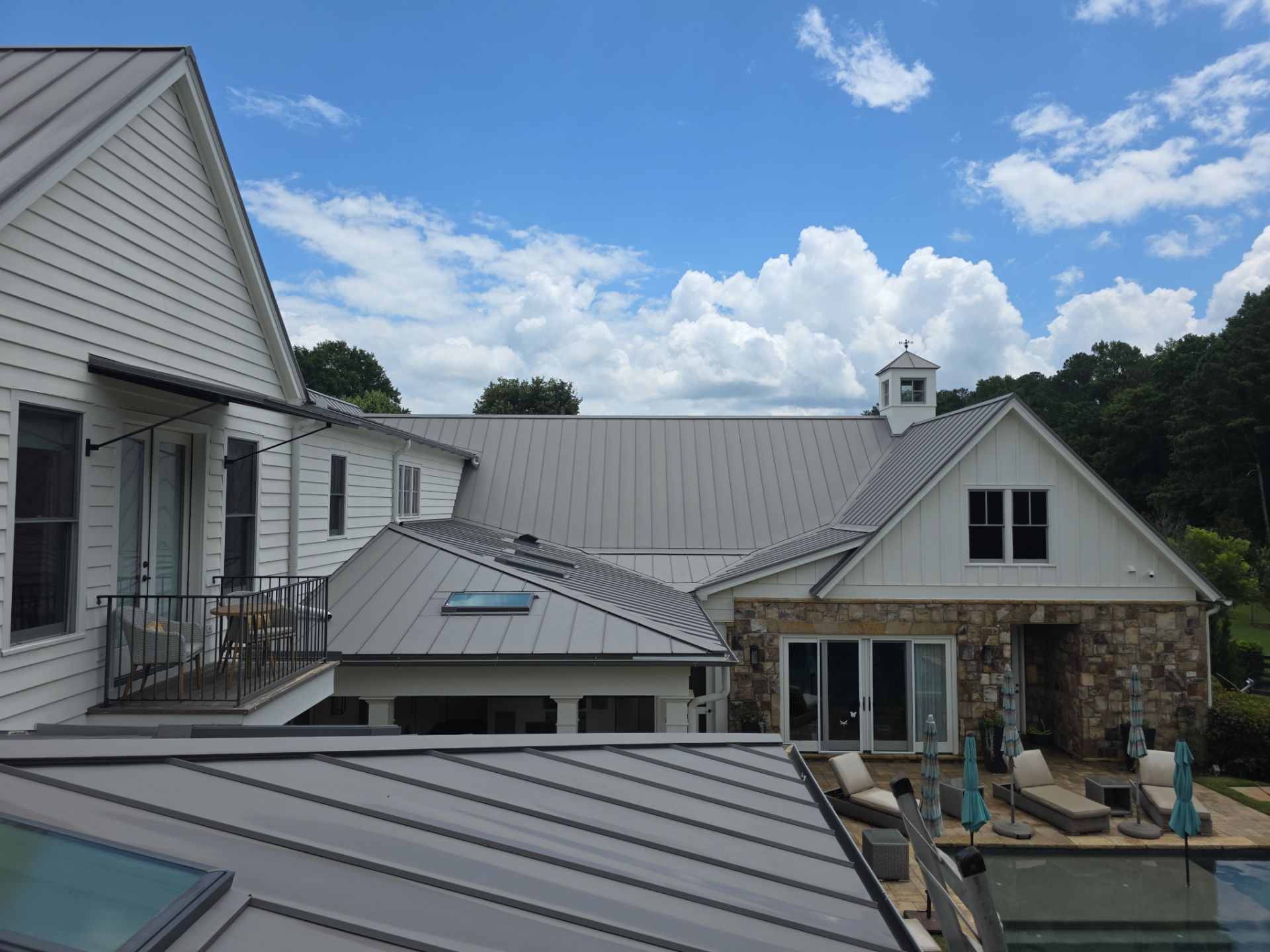 Elevated view of standing-seam metal roofs on a large residential property in Milton, GA, with pool deck visible below.