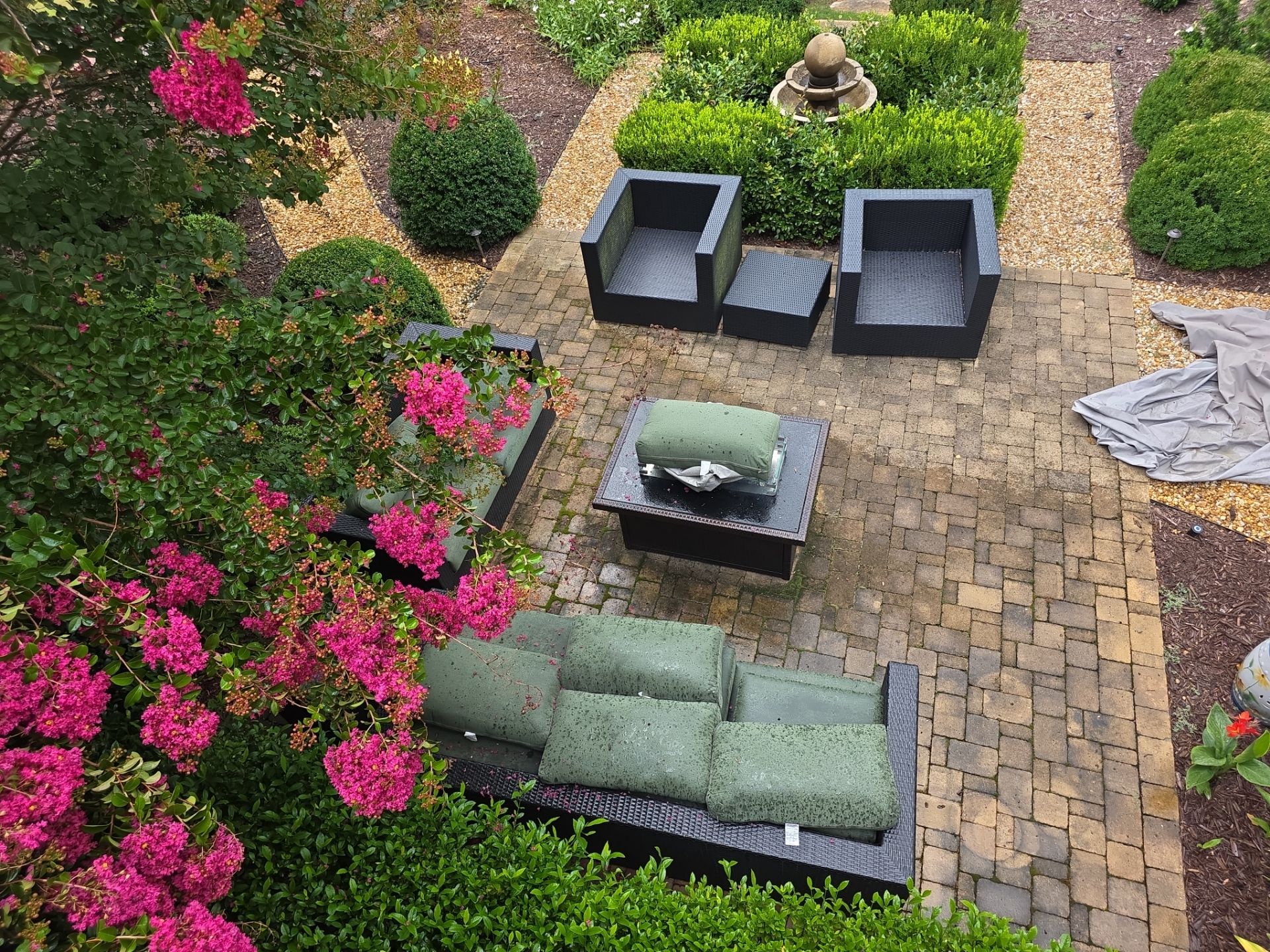 Aerial view of a brick paver patio with outdoor furniture, fire table, and formal garden at a Milton, GA residence.