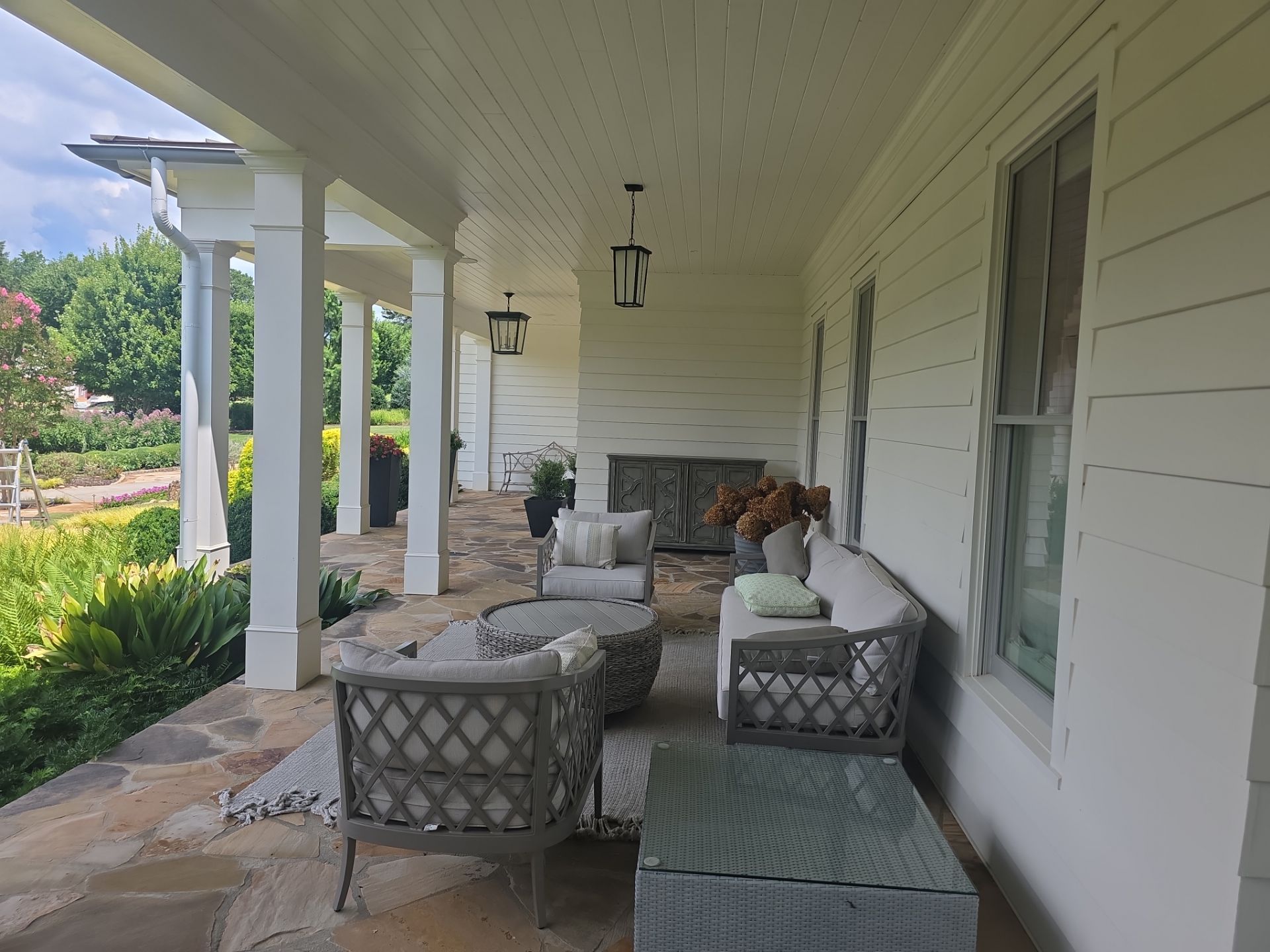 Covered front porch with flagstone floor and outdoor furniture at a Milton, GA home pressure washing job.