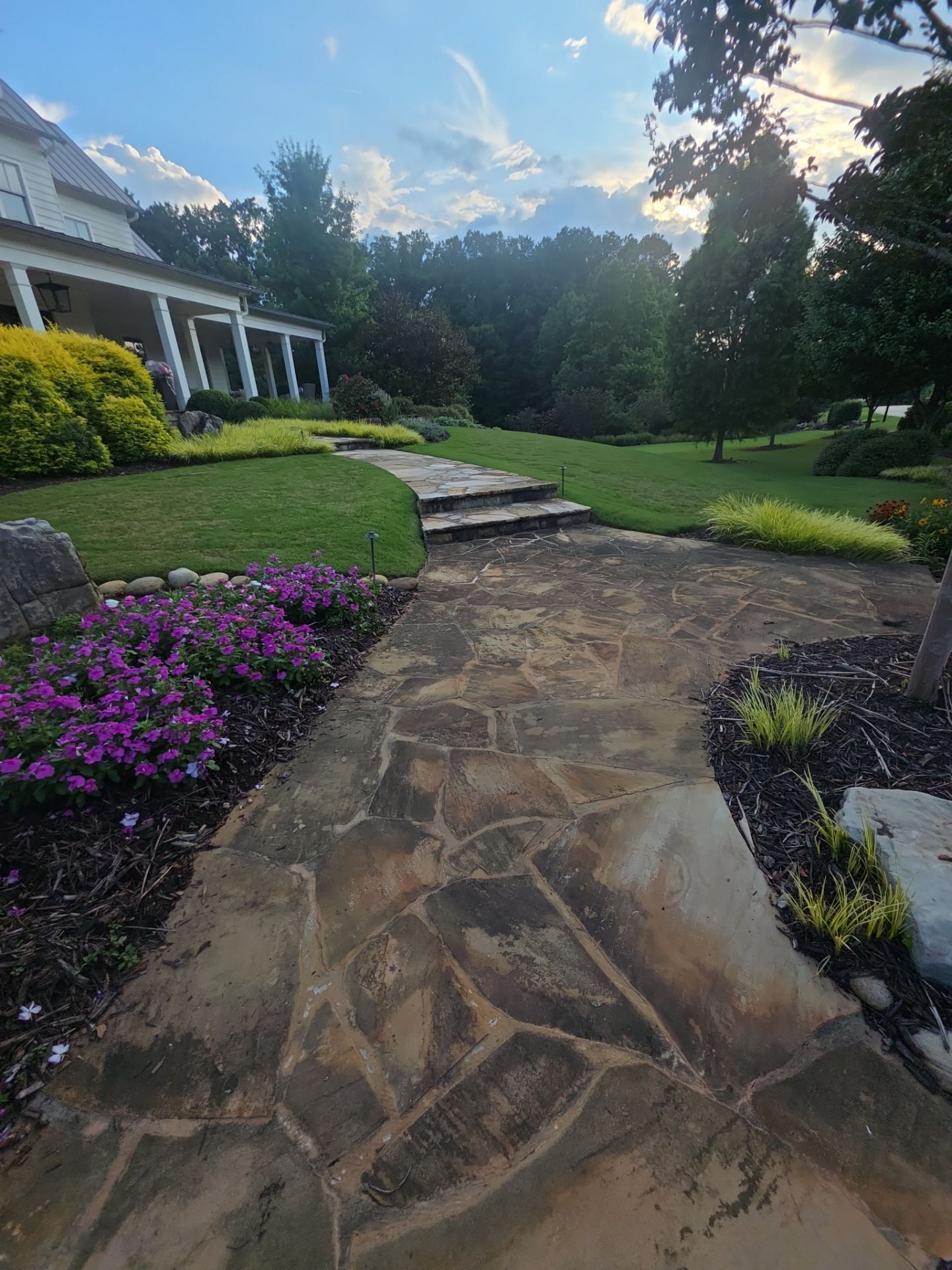 Flagstone front walkway with stone steps leading to the porch of a white farmhouse in Milton, GA.