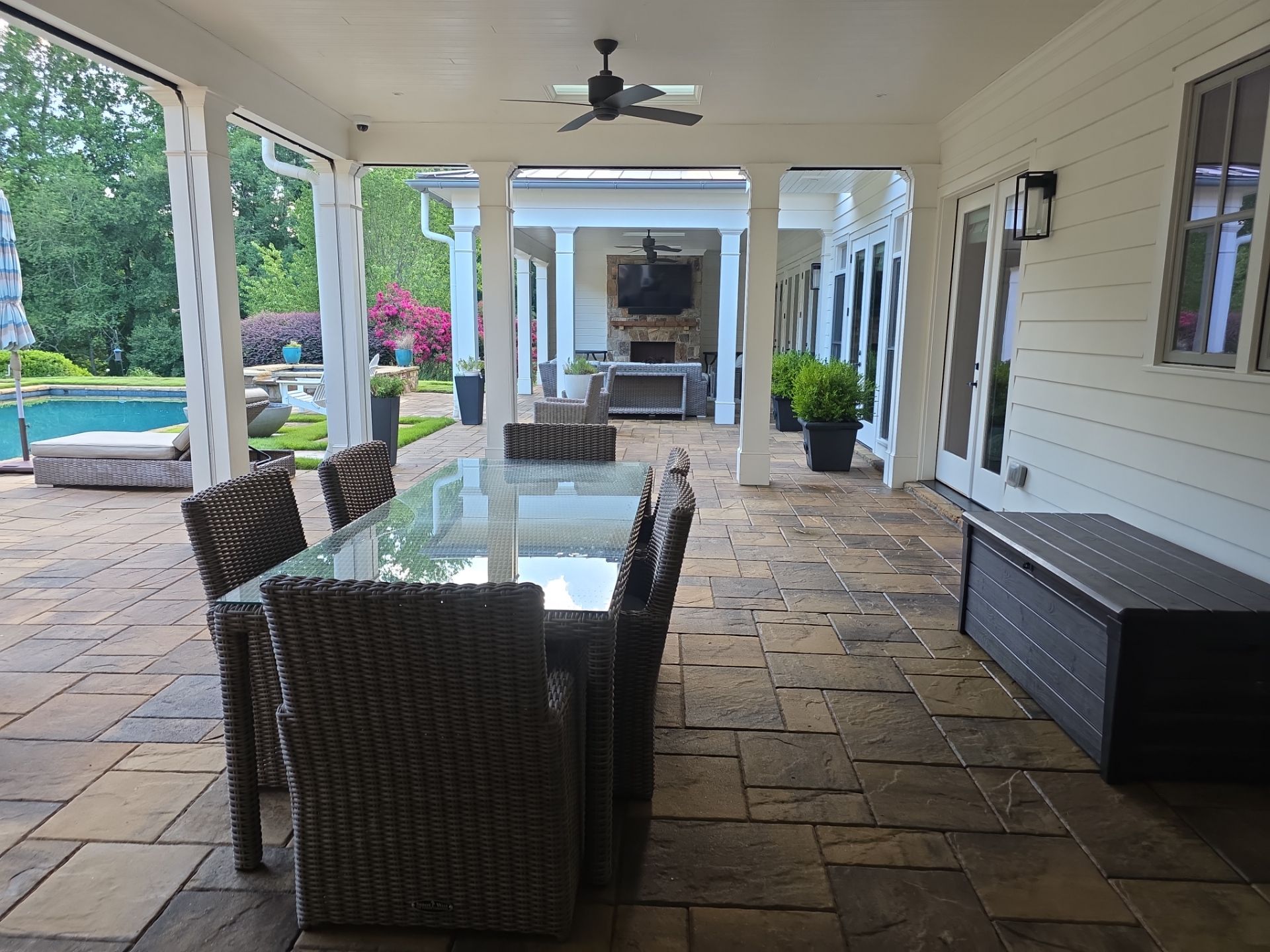 Covered outdoor dining area with stamped stone pavers, wicker furniture, and a view to the pool at a Milton, GA home.