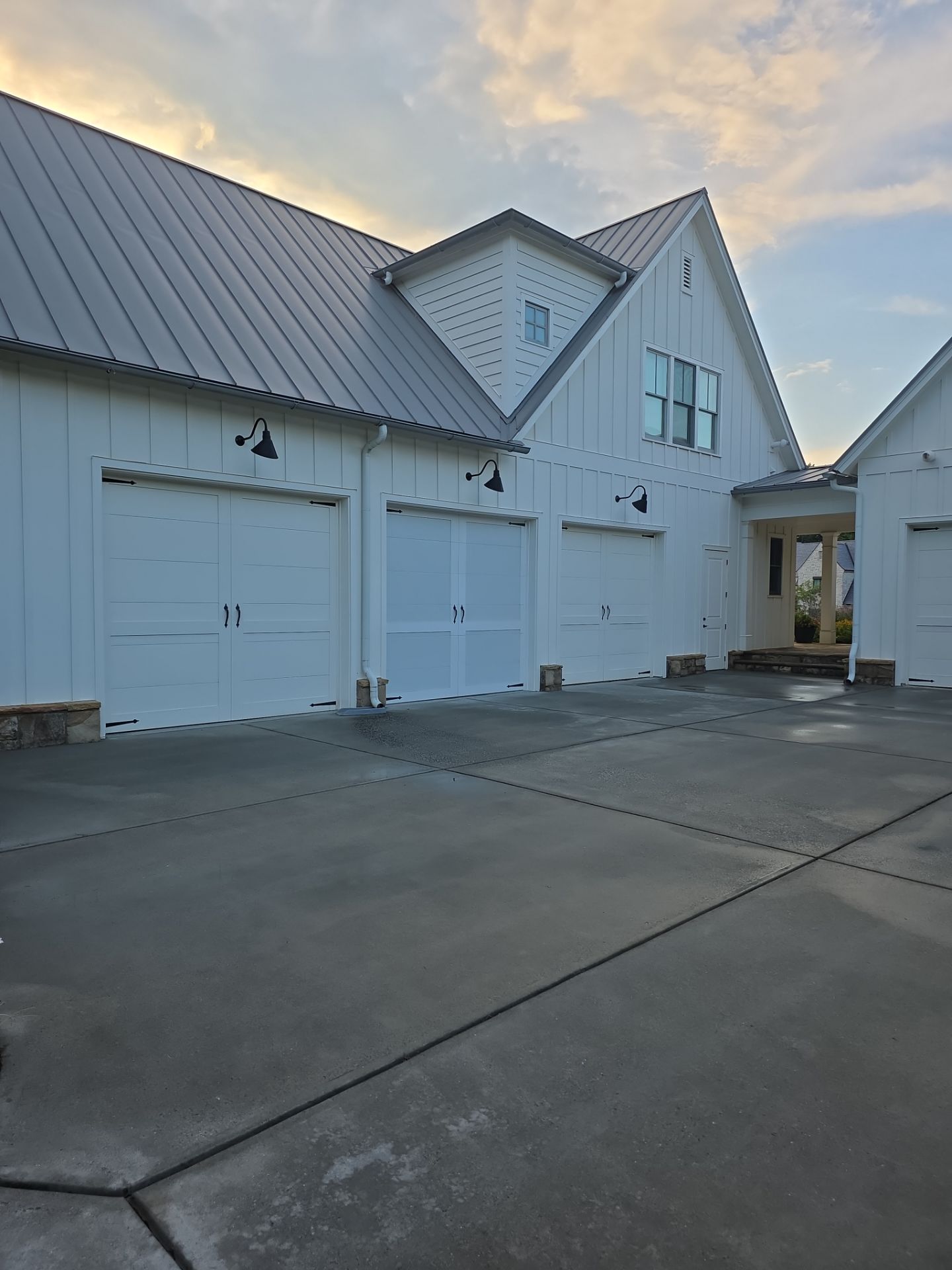 Concrete driveway in front of a three-bay white farmhouse garage with metal roof at a Milton, GA pressure washing job.
