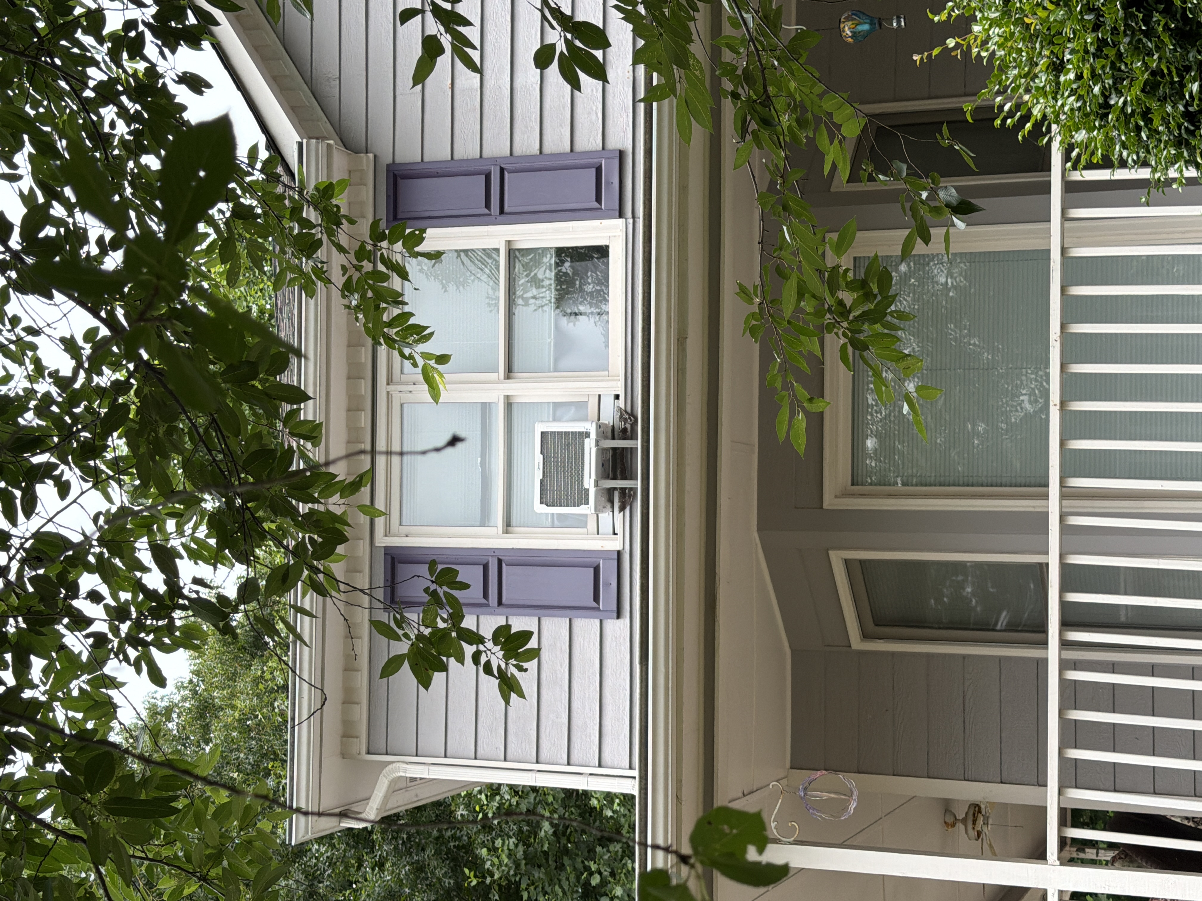 Clean gray vinyl siding and white porch on front of Canton, GA home after house washing, with purple shutters visible