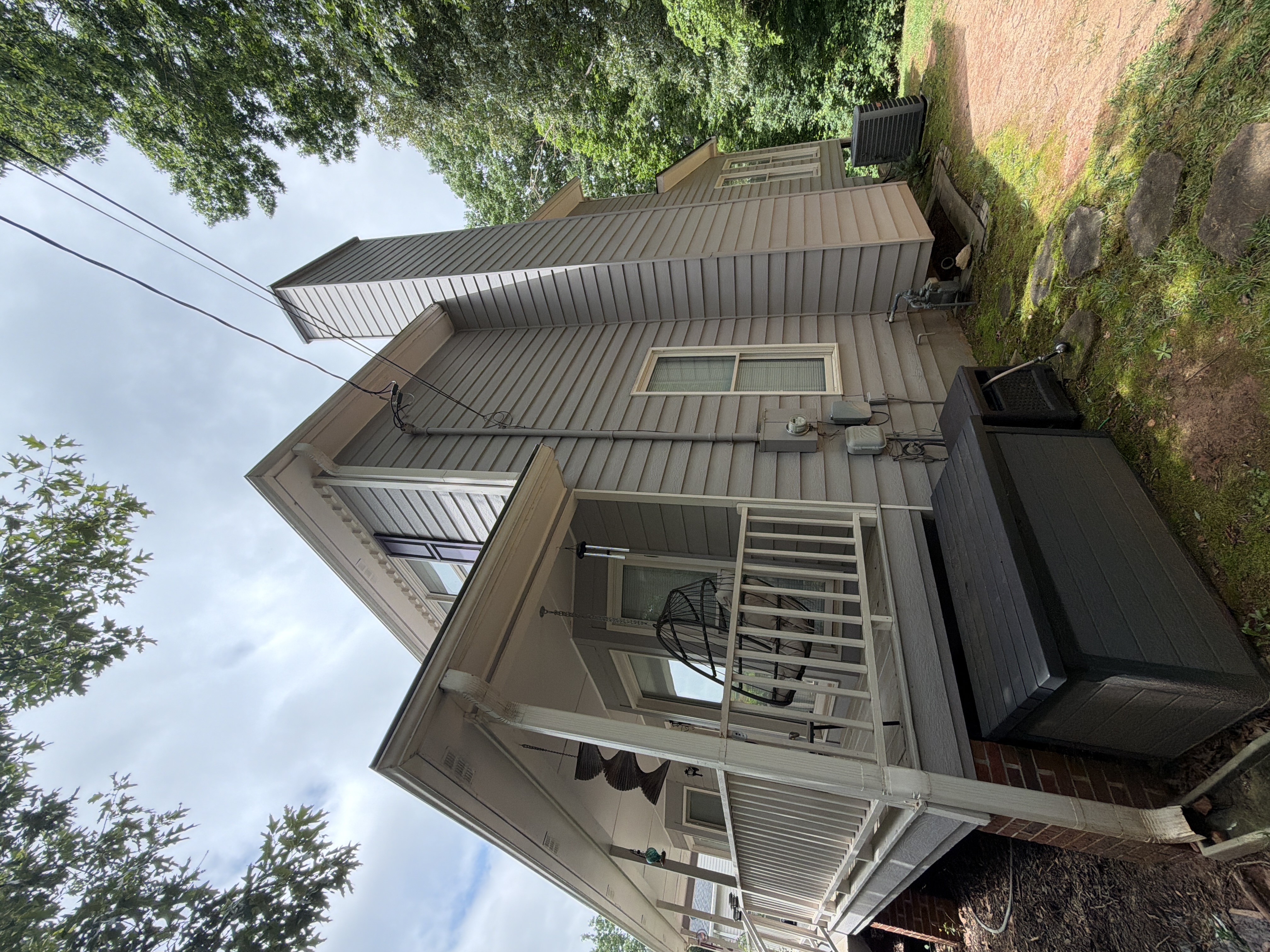 Side exterior of Canton, GA home with clean gray vinyl siding, porch, and chimney after house washing service