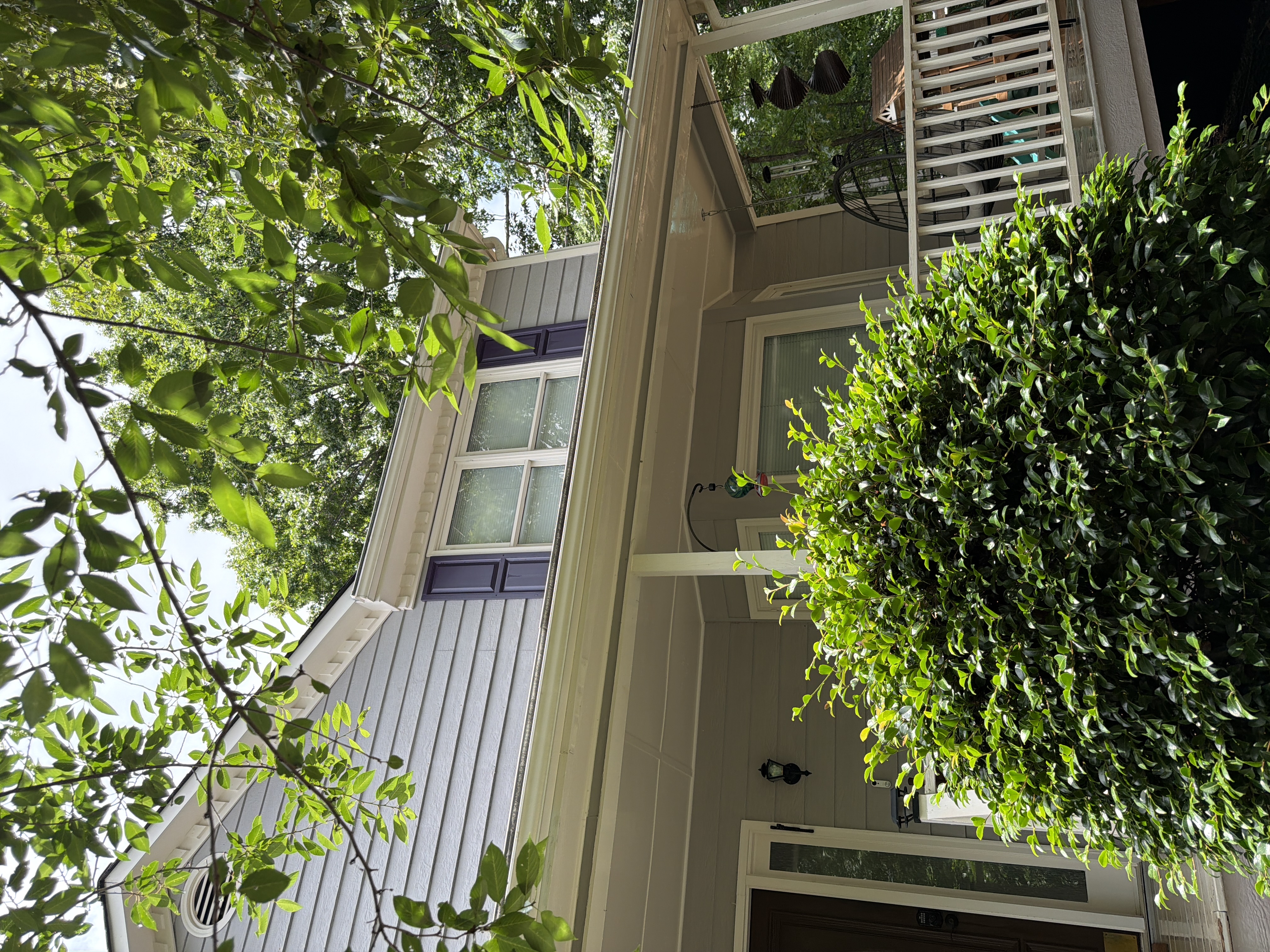Clean gray vinyl siding and white covered porch on Canton, GA home after house washing, framed by lush green trees
